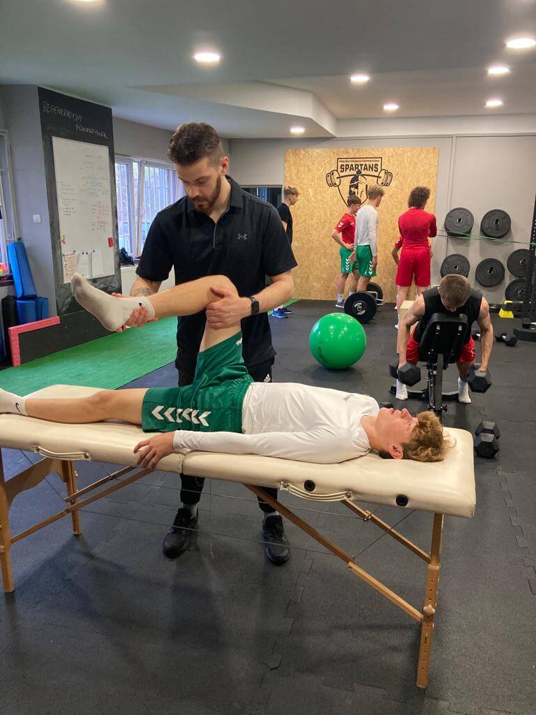 Trener przygotowania motorycznego z Warszawy podczas pracy z piłkarzem na stole treningowym